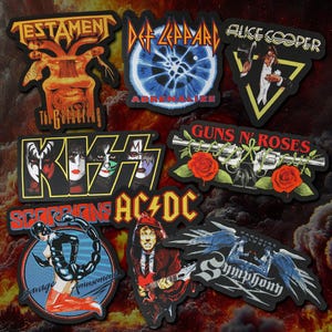 May include: A collection of eight rectangular and shaped embroidered patches featuring rock band logos and album art, including Testament, Def Leppard, Alice Cooper, Kiss, Guns N' Roses, Scorpions, AC/DC, and Symphony X with vibrant graphic designs.