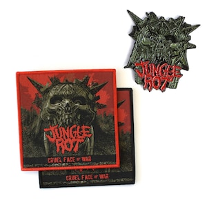 May include: Two square fabric patches and one metal pin featuring a dark green skull design with spikes. The text JUNGLE ROT is printed in red, and the text CRUEL FACE OF WAR is printed in red at the bottom of the patches. The patches have red borders.