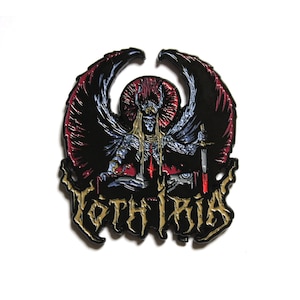 Può includere: Spilla in smalto nero e rosso raffigurante una figura scheletrica con ali, un'aureola e una spada. La spilla presenta la scritta "YOTHIRIA" in lettere dorate. Il design è dettagliato e ha un tema gotico o fantasy.