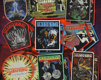 May include: A collection of embroidered fabric patches featuring various Scorpions band album artwork. The patches display diverse shapes and designs, including skulls, scorpions, and band members, with the text Scorpions printed on each piece.