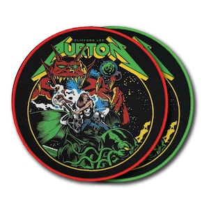 May include: Two circular embroidered patches featuring a graphic illustration of a red demon and a guitarist. The text CLIFFORD LEE BURTON is printed in green at the top. The design includes green tentacles, skulls, and a starry black background.