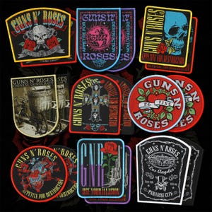 May include: A selection of embroidered patches showcasing the band Guns N' Roses. The designs incorporate skulls, roses, and the band's logo, with phrases like "Appetite for Destruction" and "Use Your Illusion". The patches are in diverse shapes and colours.