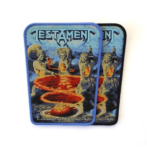 May include: Two rectangular woven patches featuring the Testament band logo at the top and the text Titans of Creation at the bottom. The design depicts figures surrounding swirling red and orange vortexes against a blue background.