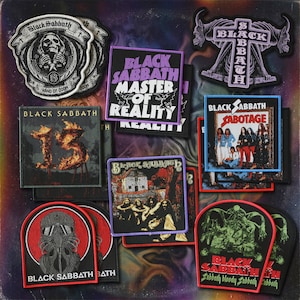 May include: A collection of Black Sabbath patches featuring various album art and logos. The patches display text such as "Master of Reality," "Sabotage," and "13." The color palette includes black, white, red, purple, and green.