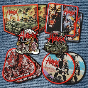 Könnte beinhalten: Eine Sammlung bestickter Stoffaufnäher mit dem Hirax-Logo und verschiedenen grafischen Illustrationen, darunter Panzer, Wölfe und Figuren. Die Aufnäher sind rechteckig, kreisförmig und individuell geformt mit leuchtend roten, orangen und schwarzen Rändern.