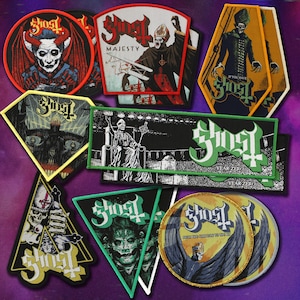 Könnte beinhalten: Eine Sammlung bestickter Stoffaufnäher mit verschiedenen Ghost-Band-Motiven, darunter kreisförmige, rautenförmige, dreieckige und sargförmige Embleme mit detaillierten Illustrationen von Figuren, Skeletten und dem Ghost-Logo in leuchtenden Farben.