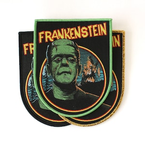 以下が含まれることがあります： 黄色い文字で「FRANKENSTEIN」と書かれた3つの黒いパッチ。パッチは、不気味な風景の背景を持つ緑色の肌のモンスターを描いています。パッチにはさまざまな色のボーダーがあります。