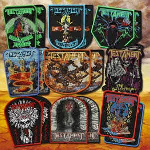 May include: A collection of embroidered fabric patches featuring the Testament band logo and various graphic illustrations including skulls, figures, and text such as Green House Effect, Into the Pit, and The Bay Strikes Back, with colorful borders.