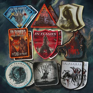 Könnte beinhalten: Eine Sammlung von aufgestickten Patches mit dem Bandnamen "IN FLAMES". Die Patches zeigen verschiedene Designs, darunter Figuren und Landschaften, mit einer Farbpalette aus Rot, Blau und Schwarz.