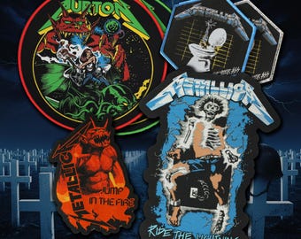 May include: A collection of four embroidered patches featuring heavy metal band imagery. Designs include a circular patch with a red demon, a hexagonal patch with a toilet graphic, a red-toned demon patch, and a blue-toned electric chair graphic.