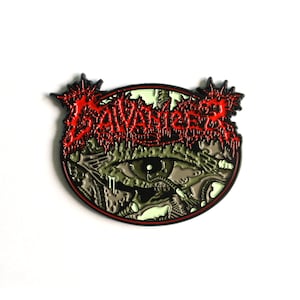 Könnte beinhalten: Eine schwarze und rote Emaille-Anstecknadel mit einem grünen und schwarzen Auge und dem Wort "SAVAGE" in roten Buchstaben.