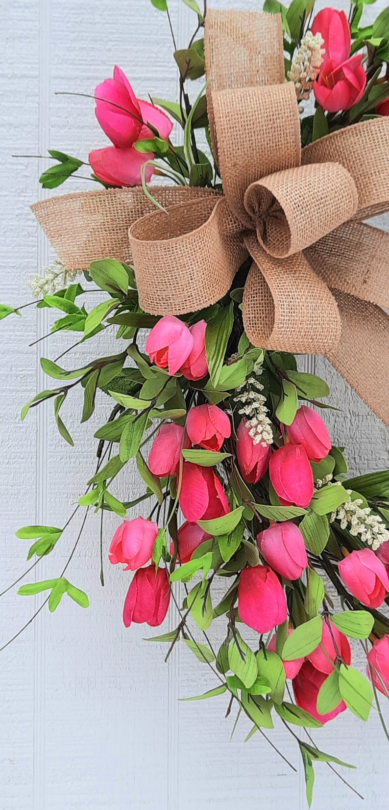 K&ouml;nnte beinhalten: Ein Kranz aus rosa Tulpen mit einer Schleife aus Sackleinen. Der Kranz besteht aus k&uuml;nstlichen Tulpen und Gr&uuml;n.