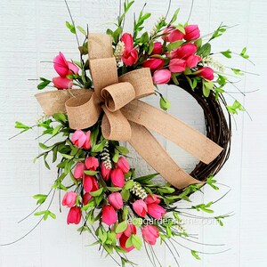 K&ouml;nnte beinhalten: Ein Kranz aus rosa Tulpen mit einer Schleife aus Sackleinen. Der Kranz ist aus Weinreben gefertigt und mit rosa Tulpen und Gr&uuml;n verziert.