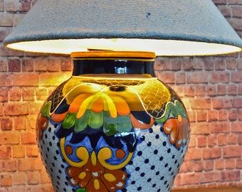 May include: A ceramic lamp base with a blue, white, and green floral design. The lampshade is a light gray fabric.