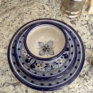 May include: A set of three blue and white ceramic plates with a floral design. The plates are nested together, with the smallest plate in the centre. The plates have a blue rim and a white centre with a blue floral design.