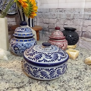 May include: Three ceramic containers with lids, decorated with blue and white Talavera pottery designs. The containers are on a granite countertop.