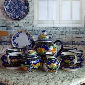 May include: A Talavera pottery tea set with a blue and white floral design. The set includes a teapot, sugar bowl, creamer, and four cups and saucers.