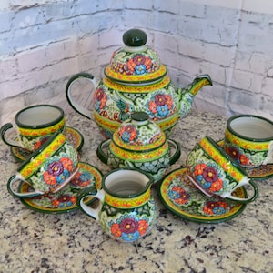 Peut inclure: Un service à thé floral vert et jaune avec une théière, un pot à crème, un sucrier et quatre tasses et soucoupes.