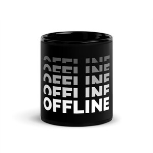Op de afbeelding: Zwarte keramische koffiemok met witte tekst die "OFFLINE" in een verlooppatroon leest.