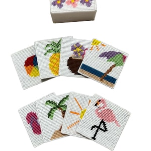Könnte beinhalten: Ein Set weißer Nadelspitzen-Untersetzer mit tropischen Designs, darunter eine Ananas, ein Flamingo und eine Strandszene. Eine passende Box mit floraler Nadelspitze ist ebenfalls enthalten. Die Untersetzer sind quadratisch und haben leuchtende Farben.