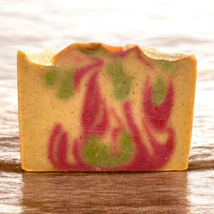 May include: A bar of handmade soap with swirls of pink, green, and yellow. The soap has a speckled appearance.