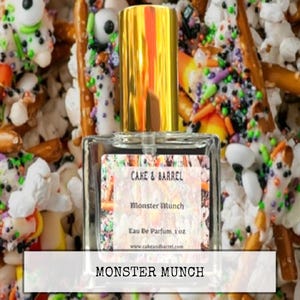 May include: A clear glass perfume bottle with a gold cap, labeled "Monster Munch" by Cake & Barrel, sits amidst a colorful assortment of Halloween-themed snacks, including pretzels and candy with sprinkles. The bottle contains 1 oz of Eau De Parfum.