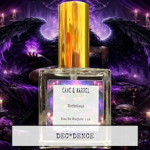May include: A rectangular glass perfume bottle with a gold cap. The label reads "Cake & Barrel Nefarious Eau De Parfum 1 oz." The background features a dark purple fantasy scene with angel wings, candles, and the word "DEC*DENCE".