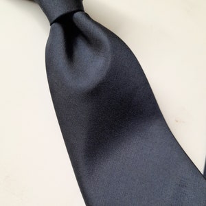 May include: A solid black silk tie. The tie is made of a smooth, high-quality fabric.