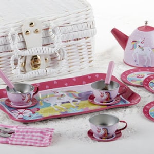 May include: A pink and white unicorn-themed children's tea set with a teapot, cups, saucers, and spoons. The set comes in a white wicker basket.