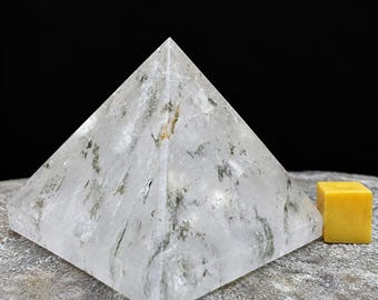 May include: A clear, pyramid-shaped crystal with internal grey and black inclusions. Next to the crystal is a small, solid yellow cube. The dimensions are printed as 48 x 47 x 39mm, which is equivalent to 1.89 x 1.85 x 1.54 inches.