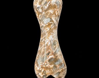 Puede incluir: Una cuenta de piedra pulida en forma de reloj de arena con una superficie texturizada veteada en tonos bronce y gris. El objeto mide 38 x 13 x 11 mm, equivalente a 1,5 x 0,51 x 0,43 pulgadas, según el texto impreso al pie de la imagen.