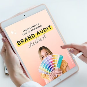 Peut inclure: Un écran de tablette affichant un graphique rose et jaune avec le texte "8 étapes simples pour faire évoluer votre marque" et "Liste de vérification de l'audit de marque". Une femme tient une palette de couleurs devant son visage.