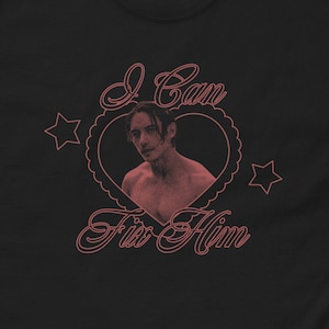 May include: Black t-shirt with a pink heart design featuring a man's face and the text "I Can Fix Him".