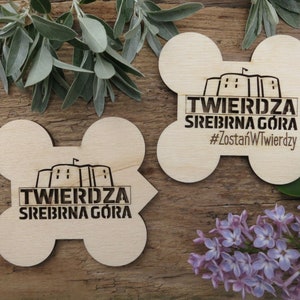 May include: Two wooden coasters with a laser-engraved design featuring a castle and the text "TWIERDZA SREBRNA G&Oacute;RA #ZostańWTwierdzy".