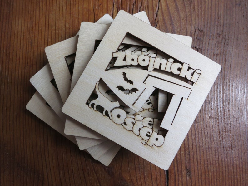 May include: A set of five wooden coasters with a laser-cut design featuring the words "Zbojnick&yacute; Ostep". The coasters are made of light brown wood and have a natural finish.