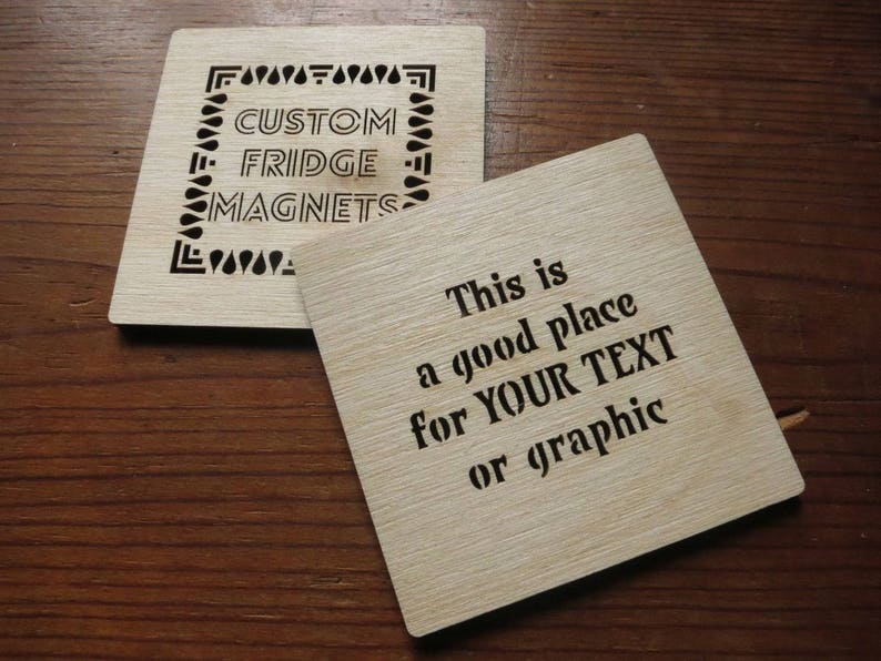 May include: Two wooden fridge magnets. One magnet has a decorative border and the text "CUSTOM FRIDGE MAGNETS". The other magnet has the text "This is a good place for YOUR TEXT or graphic".