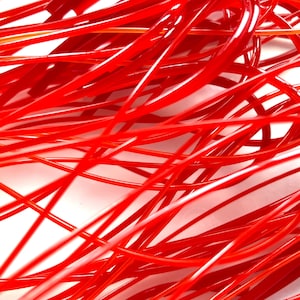 May include: A close-up of a tangled mass of bright red string. The string is thin and flexible, and it is arranged in a random pattern.