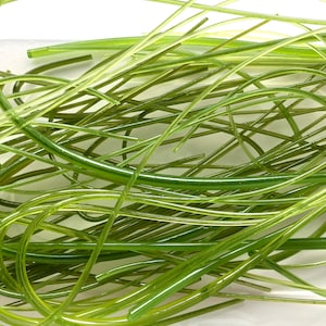 May include: A pile of thin, translucent green plastic tubes, some curved and some straight, on a white surface.