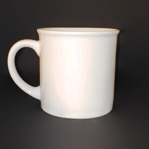 May include: A plain white ceramic mug with a rounded handle.
