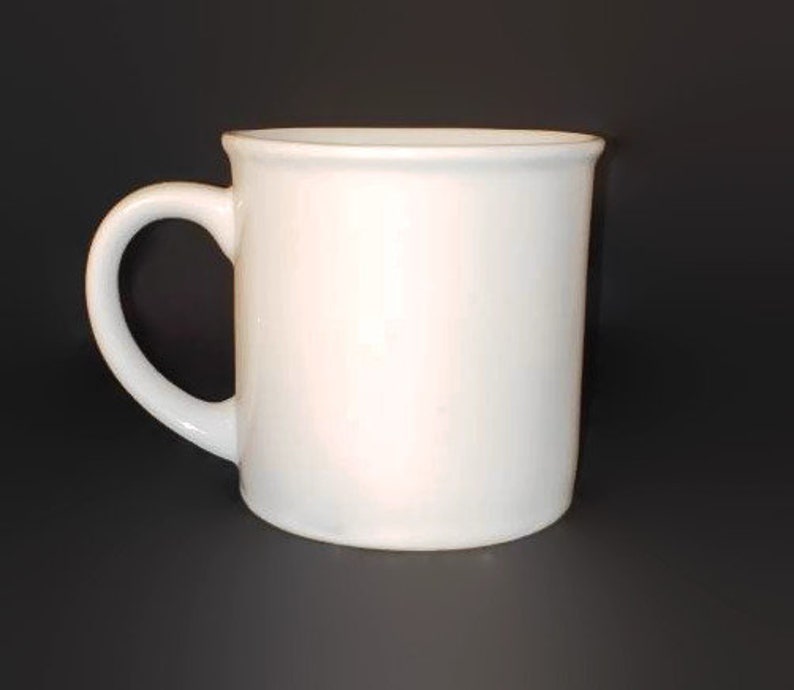 May include: A plain white ceramic mug with a rounded handle.