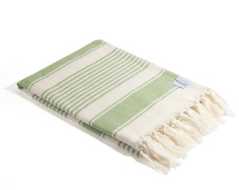 May include: A green and white striped beach towel with white fringe. The towel has a small white tag with the word "Ondalinda" on it.
