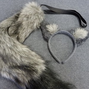May include: A gray wolf tail costume with a black strap and a gray wolf ear headband. The tail is made of faux fur and has a black tip. The headband has two gray wolf ears with white tips.