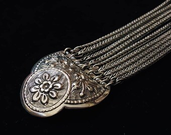 May include: A silver chain belt with a decorative, ornate buckle featuring a floral design.