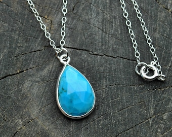 May include: A silver chain necklace with a teardrop-shaped turquoise pendant.