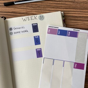 Op de afbeelding: Een open planner met week 33, met stickers voor elke dag. De planner bevat secties voor boodschappen en huiswerk. Een zwarte pen ligt op het houten oppervlak. De stickers hebben paarse en blauwe accenten. Voor het organiseren van taken.