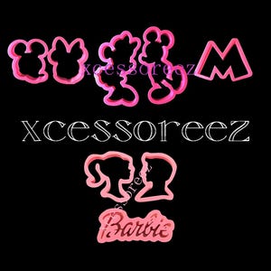 May include: Pink plastic cookie cutters in the shapes of Mickey Mouse, Minnie Mouse, a princess, a prince, a letter M, and the word "Barbie".