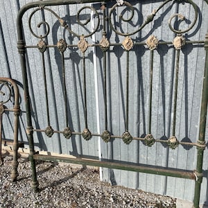 May include: A vintage green metal headboard with ornate scrollwork and decorative accents. The headboard is made of wrought iron and has a distressed finish.