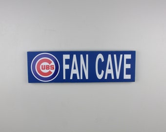 May include: Blue and white sign with the Chicago Cubs logo and the text "FAN CAVE".