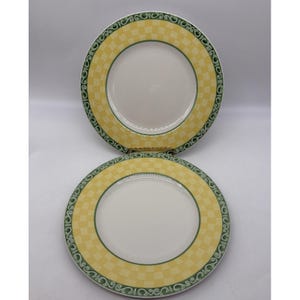 May include: Two white ceramic plates with a yellow chequered border and a green decorative edge. The plates are round and have a simple, elegant design, suitable for everyday use or special occasions.