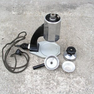 May include: A vintage silver and black electric coffee maker with a cord and a separate filter basket. The coffee maker has a round base and a tall, cylindrical top.